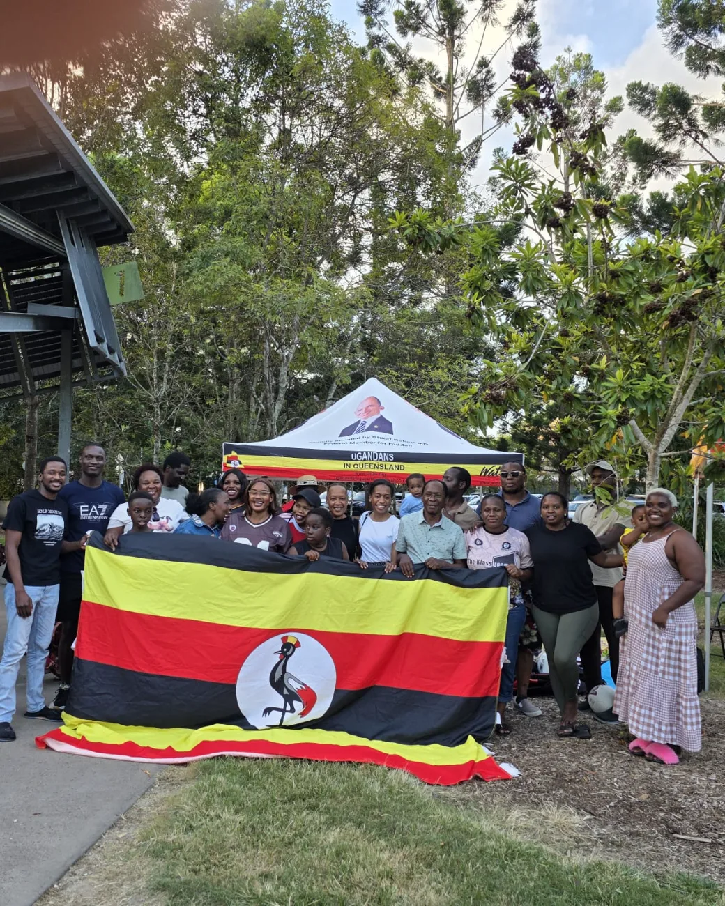 UIQ community members holding the Ugandan flag at a park gathering
